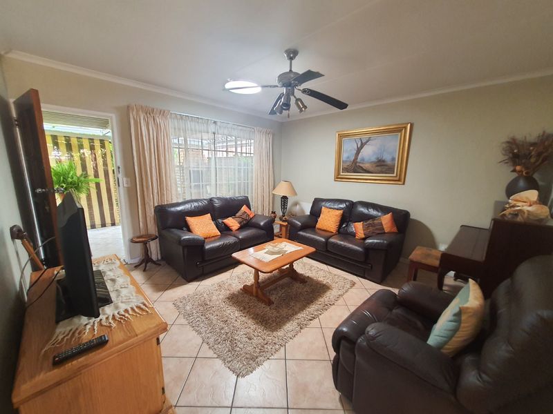 A comfortable living room featuring tiled flooring, a ceiling fan, and direct access to an outdoor patio area through a sliding glass door.