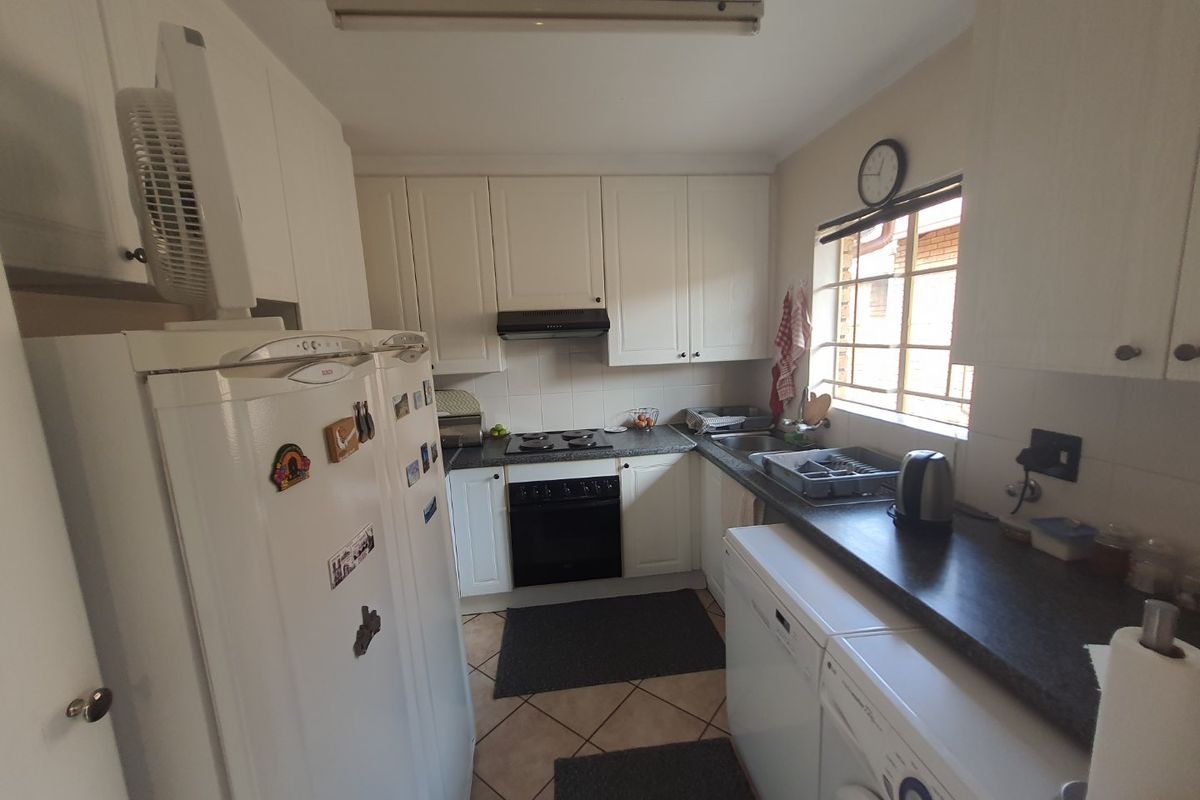 Functional kitchen featuring white cabinetry, dark laminate countertops, built-in oven, hob, extractor fan, and tiled flooring.
