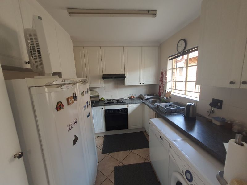 Functional kitchen featuring white cabinetry, dark laminate countertops, built-in oven, hob, extractor fan, and tiled flooring.