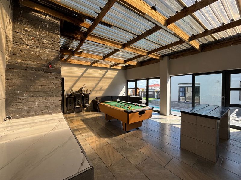 Covered outdoor entertainment area featuring a built-in fireplace, tiled flooring, and a translucent roof, providing a versatile space for leisure and social gatherings.
