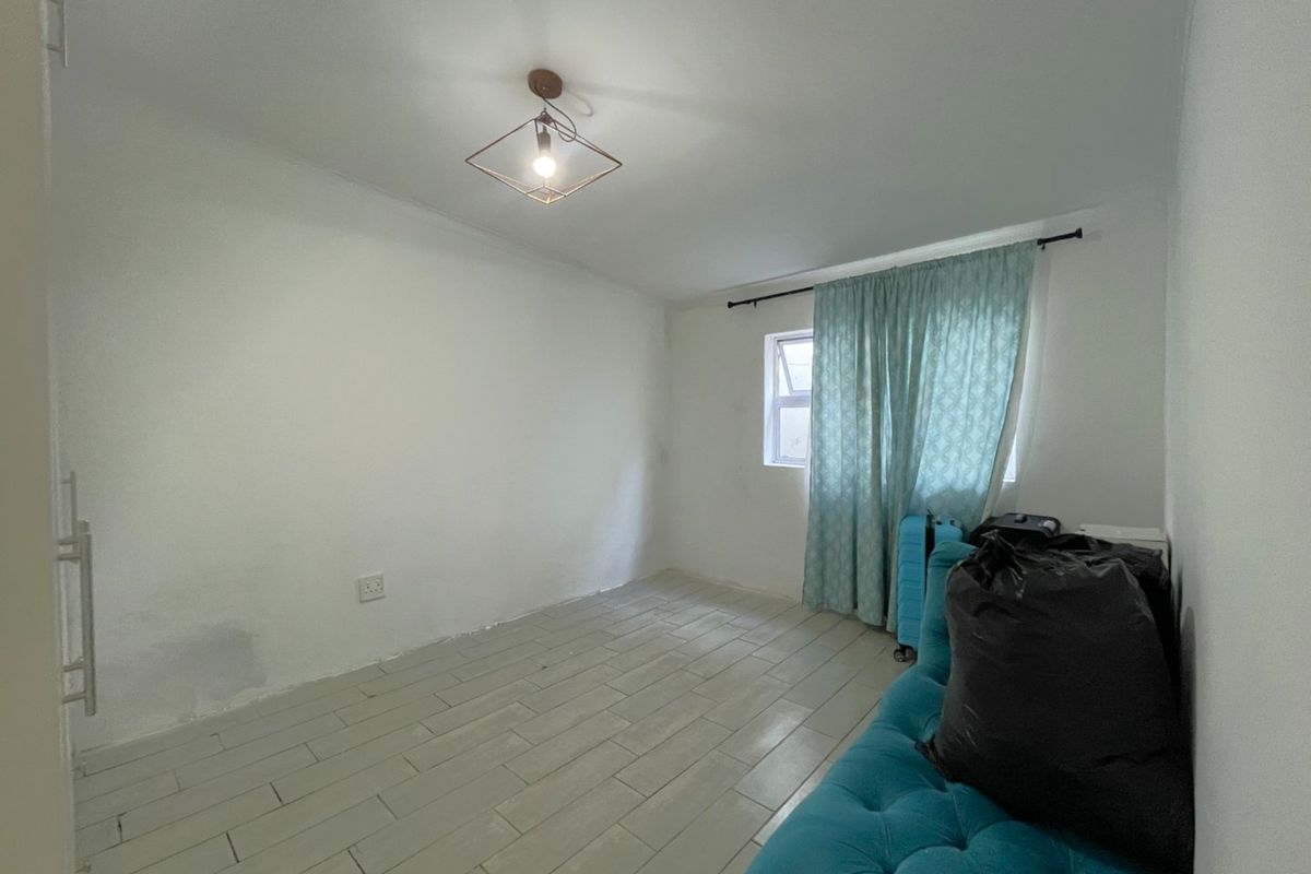 A bedroom featuring tiled flooring and a central light fixture, currently requiring cosmetic updates to the wall finishes.
