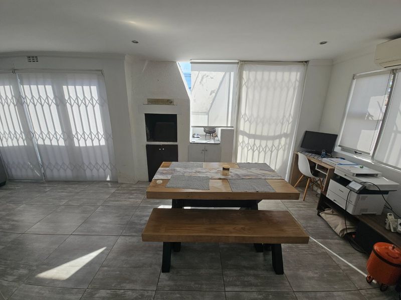 Open-plan living area featuring tiled floors, a built-in braai, and security gates leading to outdoor access.