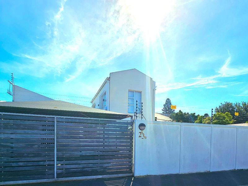 Front exterior view of the property featuring a timber slat gate, concrete boundary wall, and electric fencing.