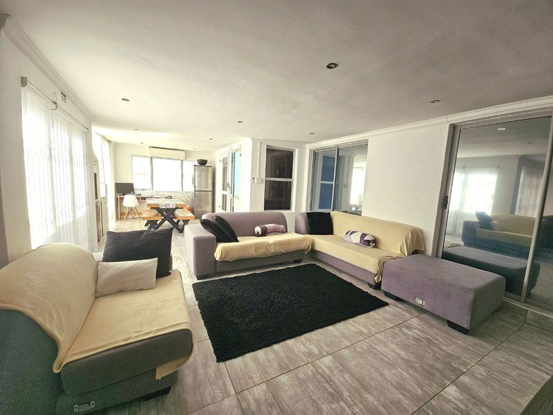 Spacious open-plan living area featuring tiled flooring, recessed lighting, and large sliding glass doors providing access to the exterior.