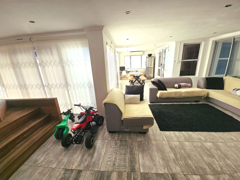 Spacious open-plan living area featuring tiled flooring, recessed lighting, and direct access to outdoor spaces through sliding glass doors.