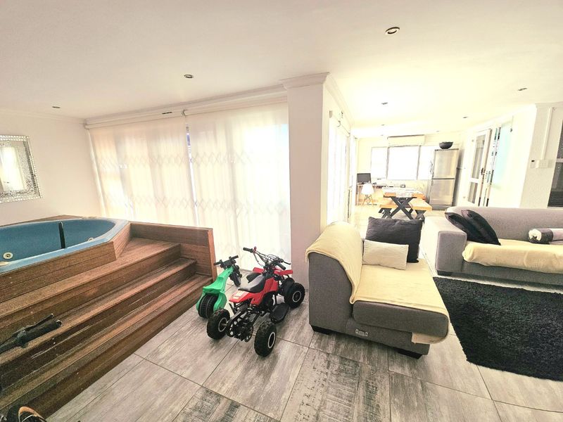 Open-plan living area featuring a built-in indoor jacuzzi, tiled flooring, and recessed lighting, creating a versatile space for relaxation and entertainment.