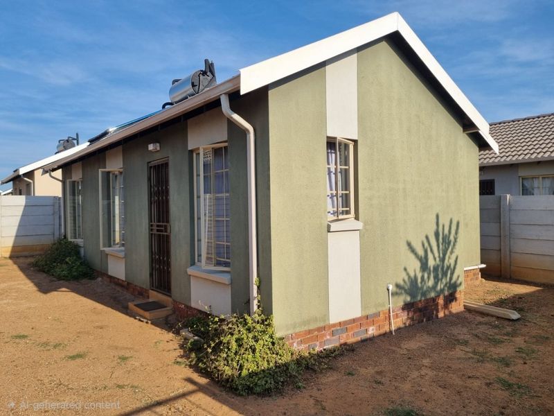 Rear view of a single-story house featuring a solar water heater, security gate, and brick plinth foundation with surrounding open yard space.