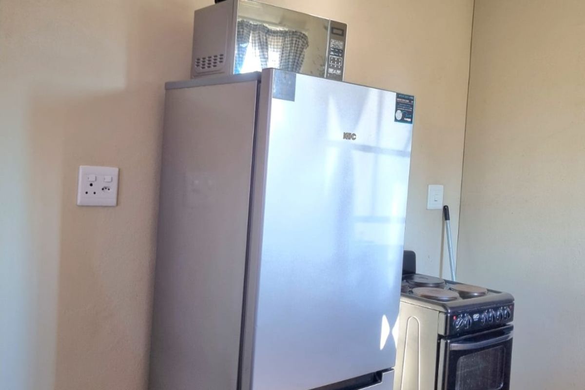 A functional kitchen area featuring ceramic floor tiles, a freestanding electric stove, and neutral wall finishes.