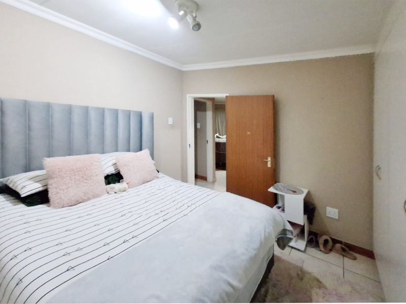 A functional bedroom featuring built-in cupboards, tiled flooring, and decorative cove cornicing, providing a neutral base for personalization.