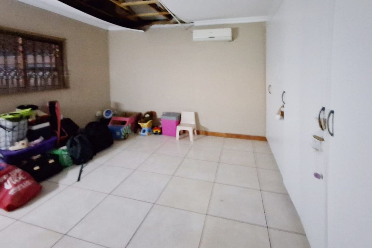 Bedroom featuring tiled flooring, built-in cupboards, and a split-system air conditioner. Note the significant damage to the ceiling requiring repair.