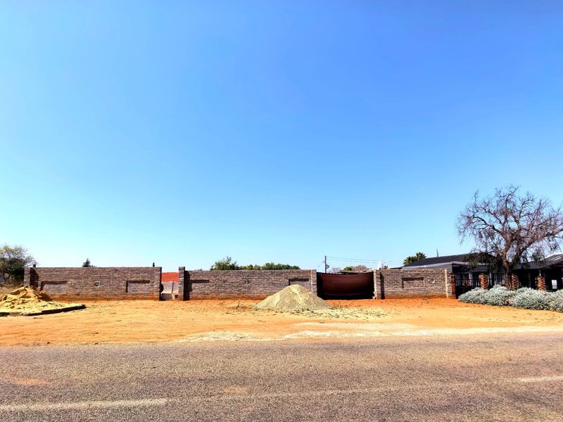 A vacant residential plot featuring a perimeter brick wall, offering a clear space ready for development.
