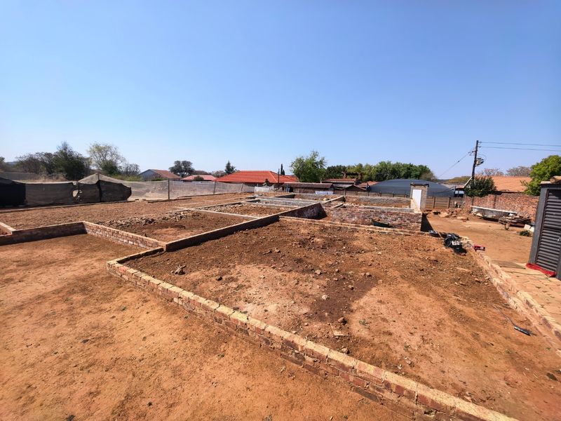 A vacant residential plot featuring an exposed brick foundation and ongoing construction work in a suburban setting.