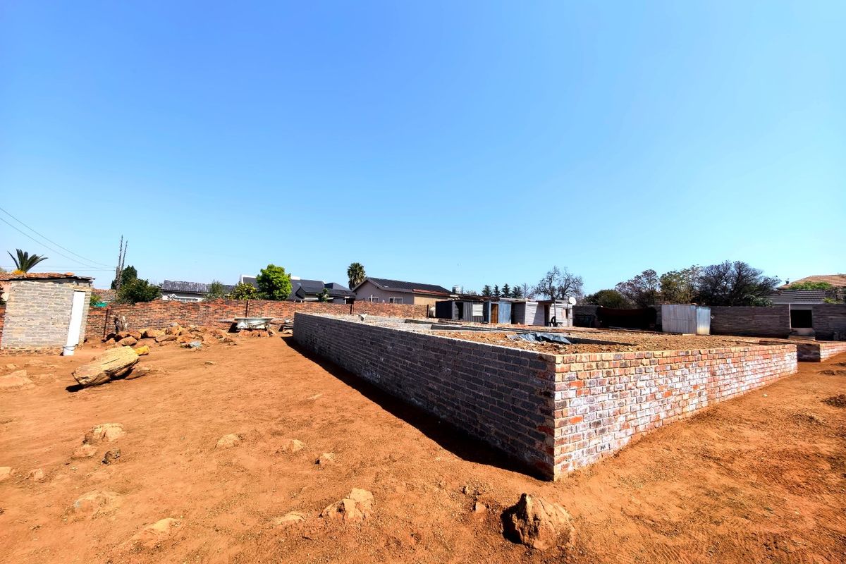 Vacant residential land featuring a brick foundation for a new build and a perimeter boundary wall.