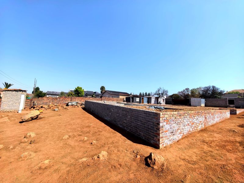 Vacant residential land featuring a brick foundation for a new build and a perimeter boundary wall.