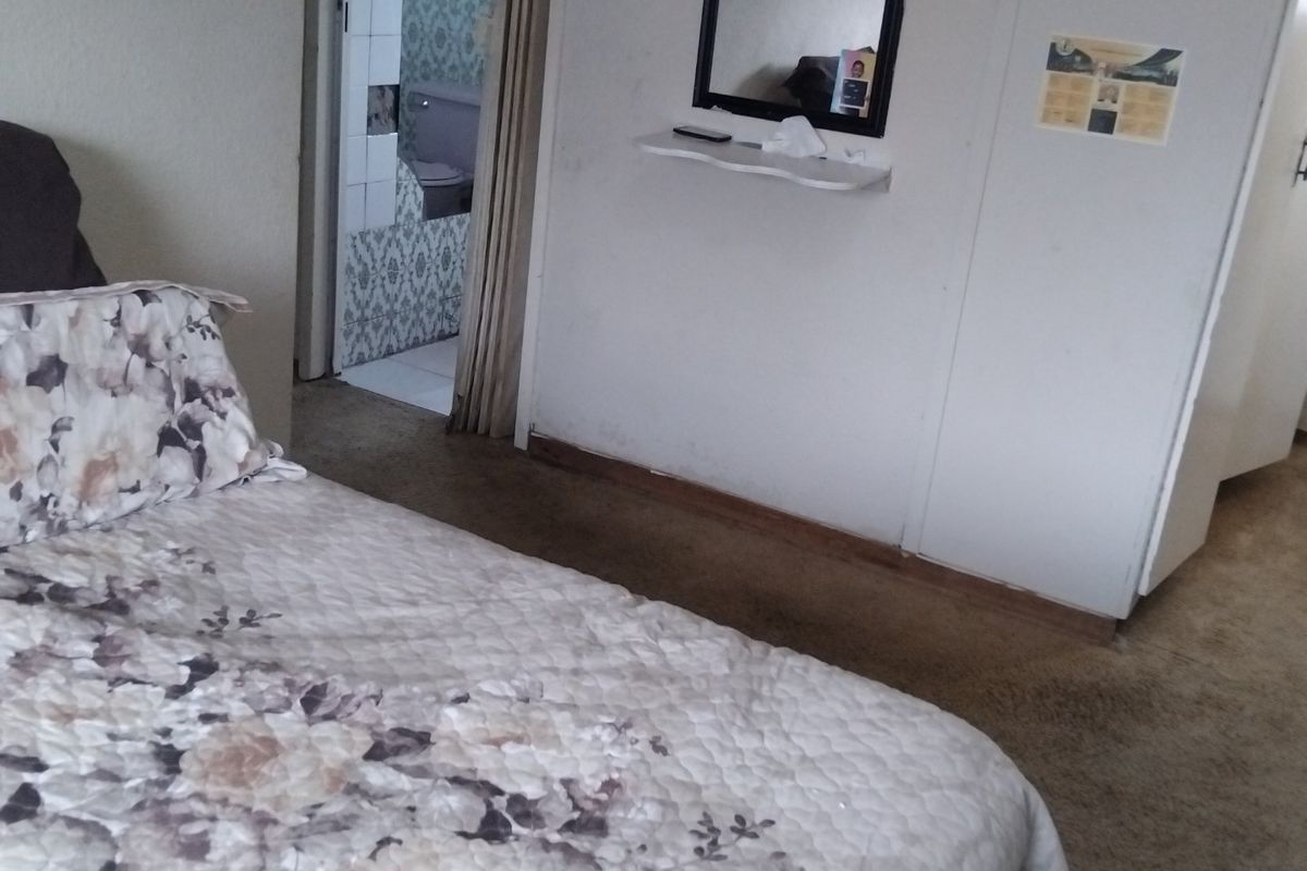 A bedroom featuring built-in cupboards and carpeted flooring, with an adjacent bathroom visible through the doorway.