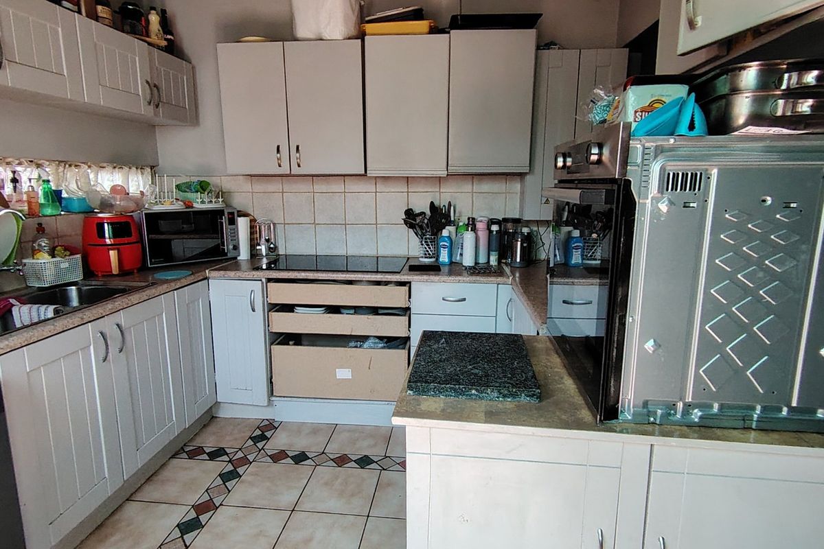 A functional kitchen featuring built-in cabinetry, laminate countertops, and integrated appliances, currently showing signs of wear and requiring minor repairs.