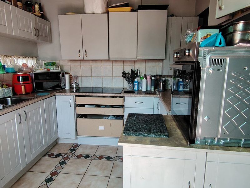 A functional kitchen featuring built-in cabinetry, laminate countertops, and integrated appliances, currently showing signs of wear and requiring minor repairs.
