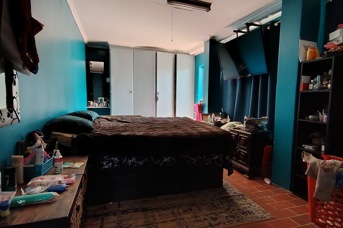 A bedroom featuring built-in cupboards and tiled flooring, offering a functional space with potential for cosmetic updates.