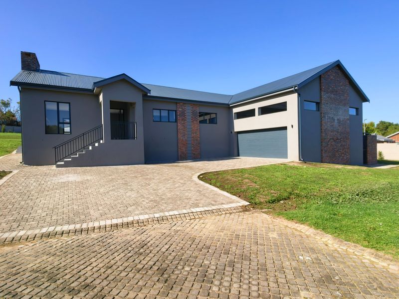 Modern double-story house exterior featuring a brick and rendered facade, metal roof, paved driveway, and integrated garage.