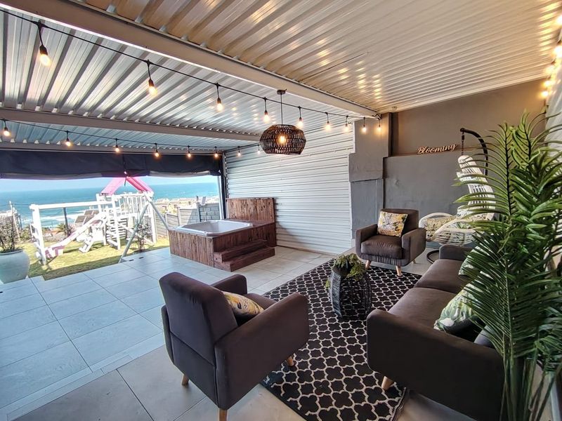 Covered outdoor patio featuring tiled flooring, a built-in hot tub, and ocean views, creating an ideal space for relaxation and entertainment.