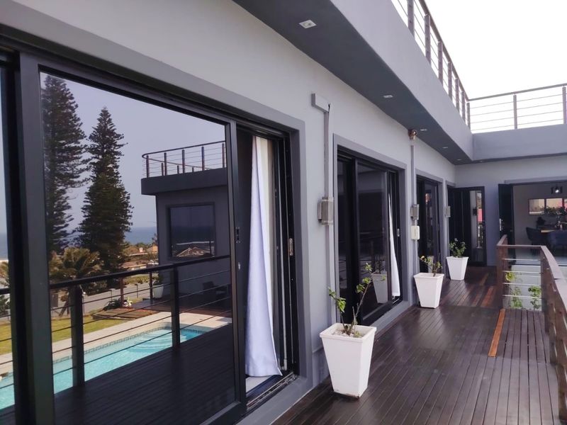 Spacious upper-level balcony featuring timber decking, modern sliding glass doors, and a metal balustrade, offering a seamless transition to outdoor living.