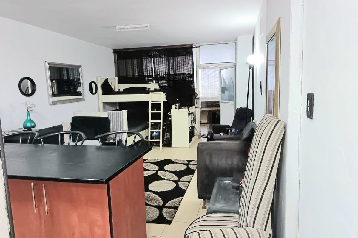 Open plan living area featuring a kitchen island and tiled flooring, with direct access to an adjoining balcony space.