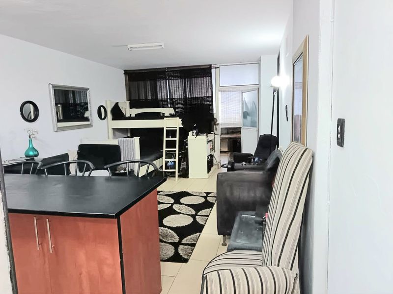 Open plan living area featuring a kitchen island and tiled flooring, with direct access to an adjoining balcony space.