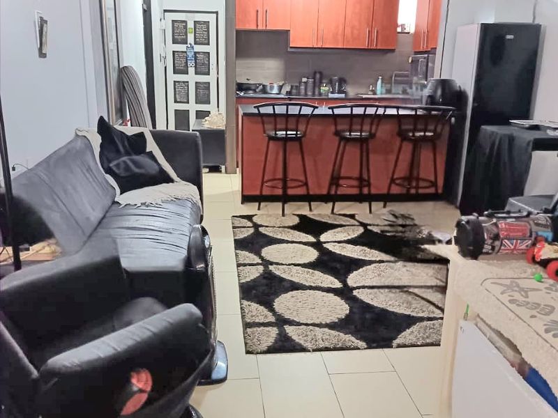 Open plan living area featuring a kitchen with built-in cabinetry and a breakfast bar, finished with tiled flooring throughout.