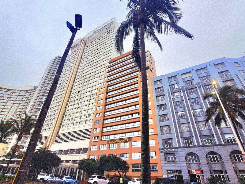 Low-angle exterior view of the Golden Sands apartment building and surrounding high-rise residential structures along the street.