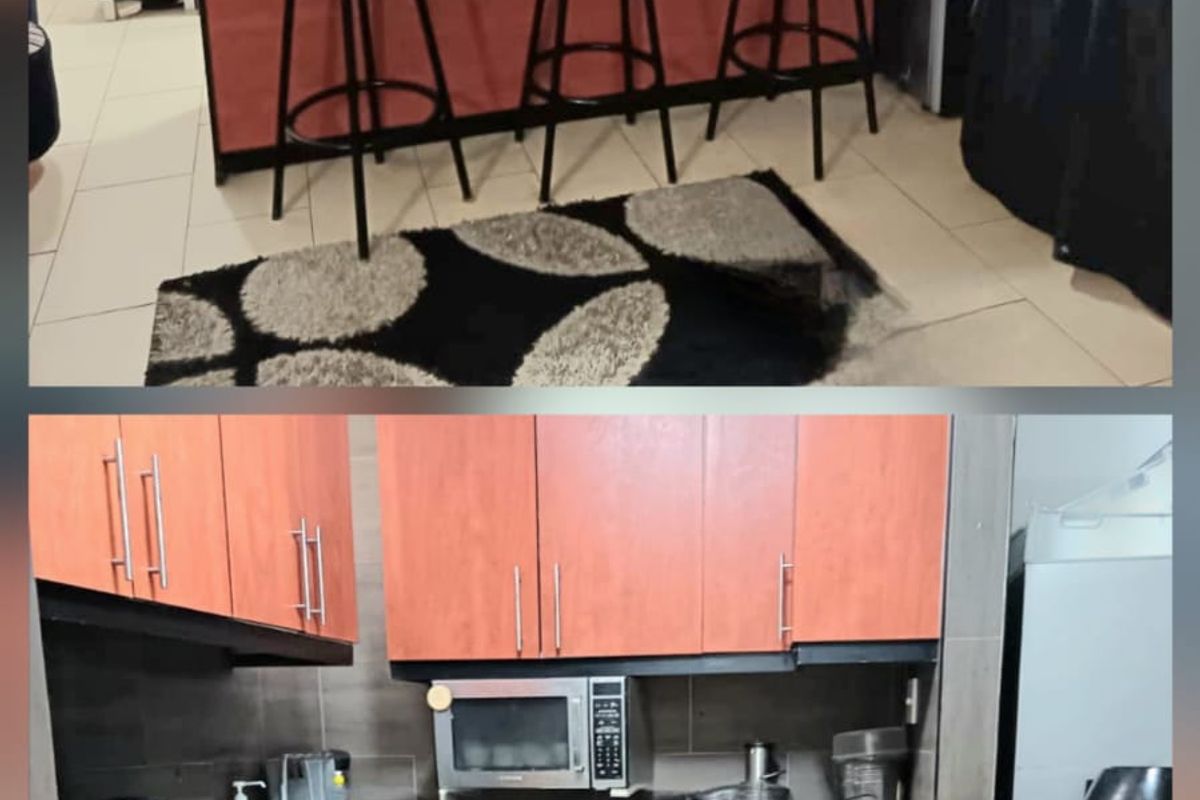 A functional kitchen featuring wood-finish cabinetry, dark countertops, and tiled flooring, providing a practical workspace with integrated storage and appliance areas.