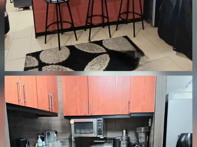 A functional kitchen featuring wood-finish cabinetry, dark countertops, and tiled flooring, providing a practical workspace with integrated storage and appliance areas.
