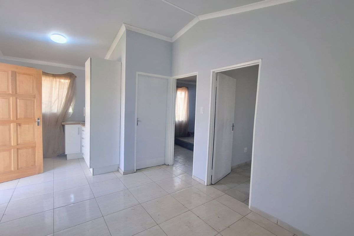 Open plan living area featuring tiled flooring, neutral walls, and access to adjacent rooms through internal doors.