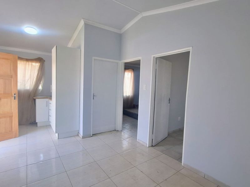 Open plan living area featuring tiled flooring, neutral walls, and access to adjacent rooms through internal doors.