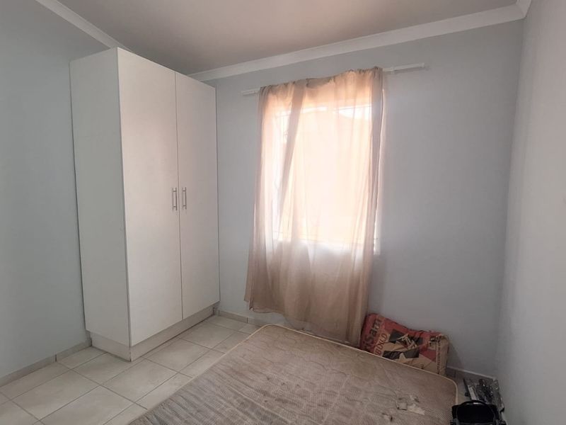 A simple bedroom featuring tiled flooring and a built-in wardrobe, offering a clean and functional space ready for personalization.