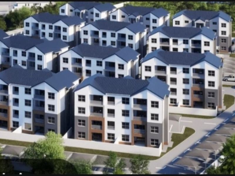 Aerial view of a modern residential apartment complex featuring multiple multi-story buildings, paved parking areas, and covered carports.