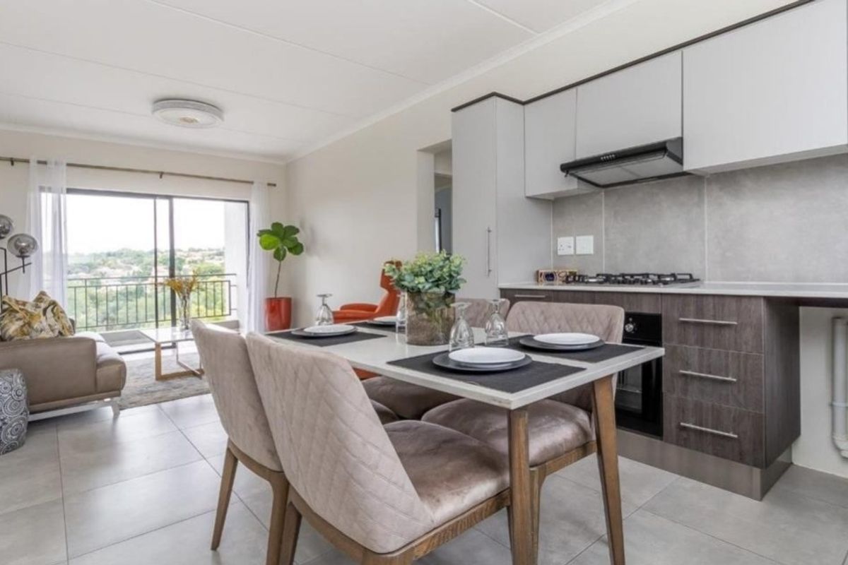 Modern open-plan living area featuring a contemporary kitchen with built-in appliances, tiled floors, and seamless access to a private balcony with scenic views.
