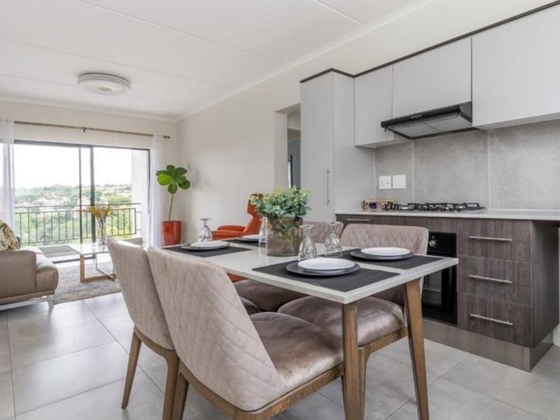 Modern open-plan living area featuring a contemporary kitchen with built-in appliances, tiled floors, and seamless access to a private balcony with scenic views.