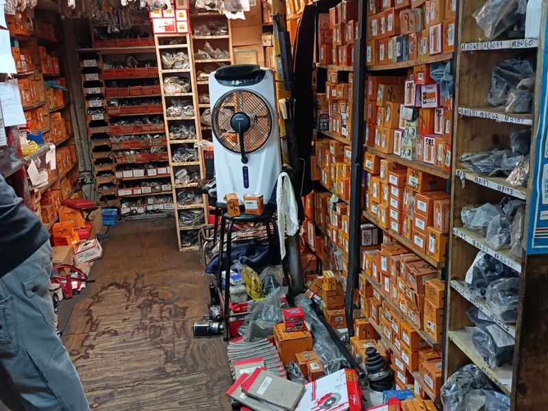 A commercial utility storage space featuring extensive built-in timber shelving units filled with inventory and worn timber flooring.