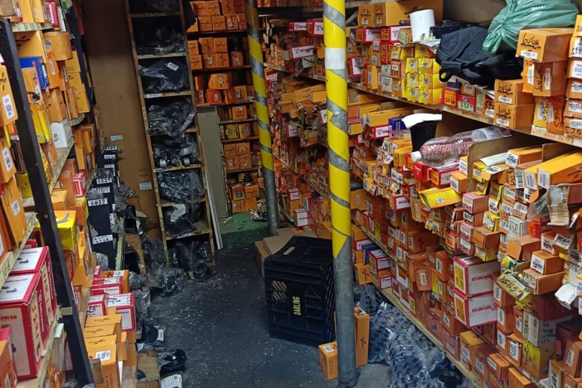 A commercial storage or utility space featuring extensive built-in shelving units packed with inventory, supported by structural columns.