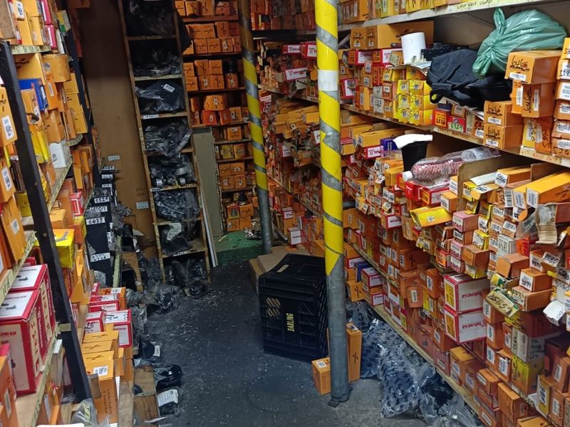 A commercial storage or utility space featuring extensive built-in shelving units packed with inventory, supported by structural columns.