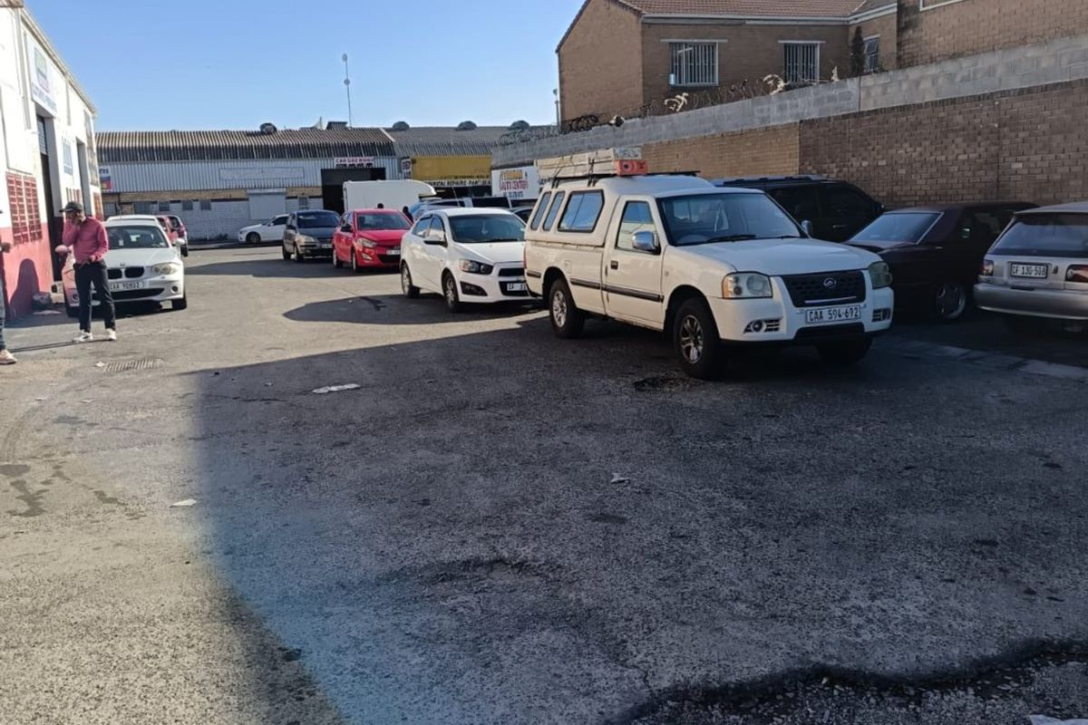 Commercial rear yard area featuring asphalt paving, enclosed by a perimeter brick wall with security fencing.