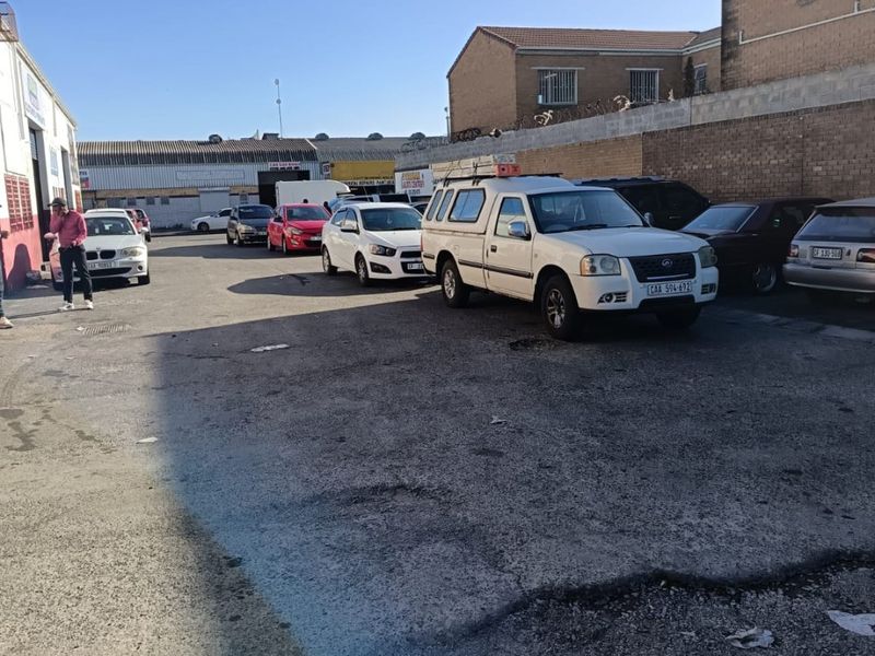 Commercial rear yard area featuring asphalt paving, enclosed by a perimeter brick wall with security fencing.