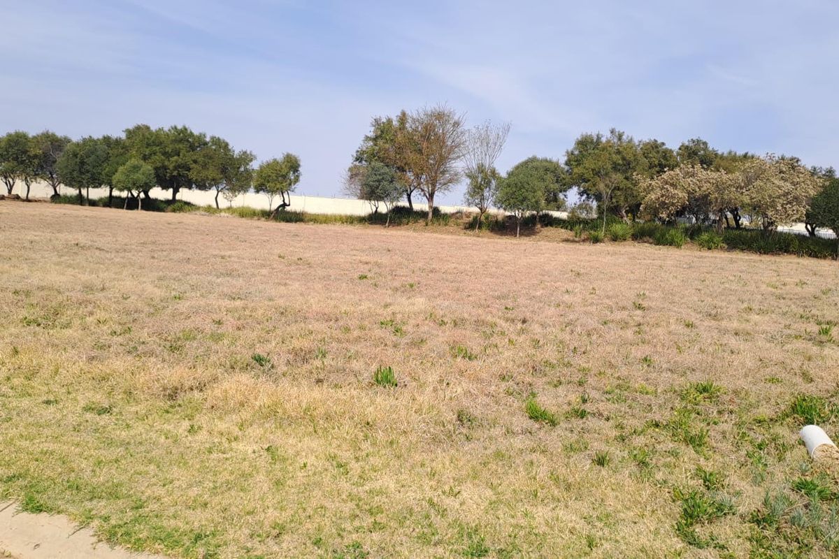 A wide, open grassed plot featuring established trees along the perimeter, offering a spacious outdoor area.