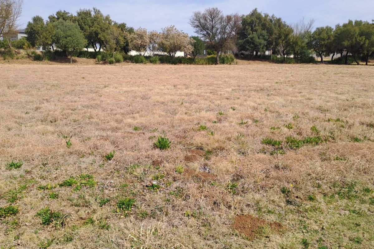 A wide, open grass field with mature trees along the perimeter, offering a spacious outdoor area.