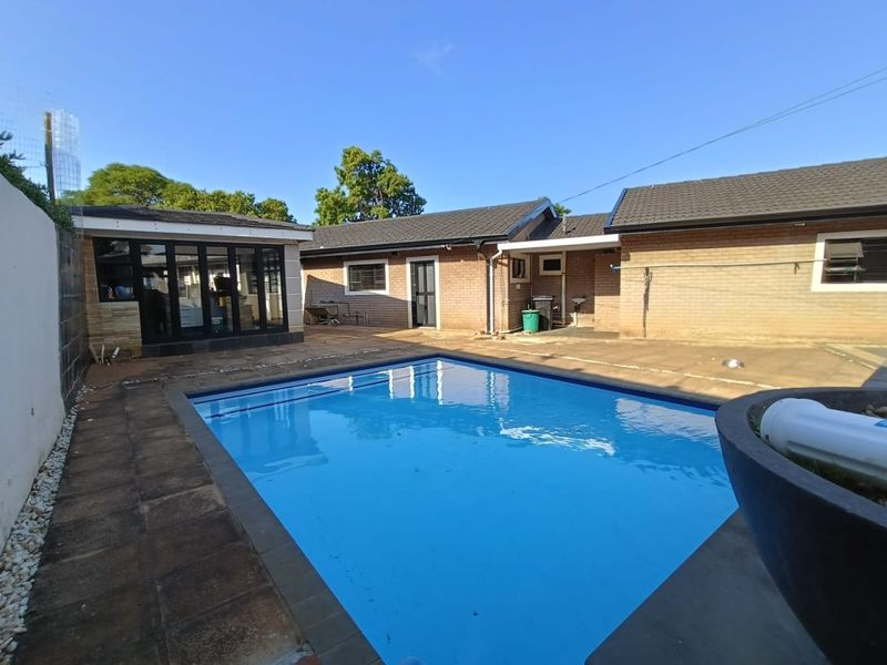 Outdoor pool area featuring a swimming pool, paved patio space, and brick exterior walls with access to the main dwelling.