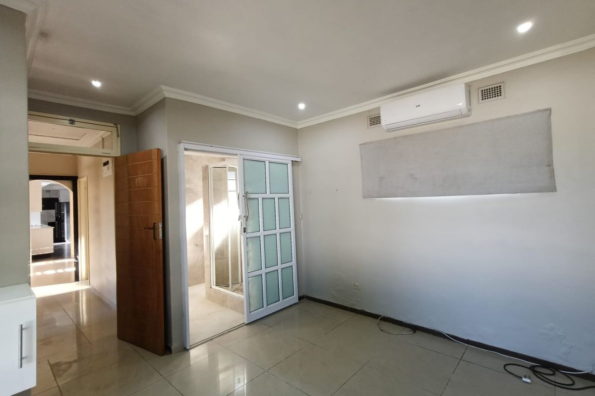 Spacious bedroom featuring tiled flooring, recessed lighting, an integrated air conditioning unit, and direct access to an en-suite bathroom.