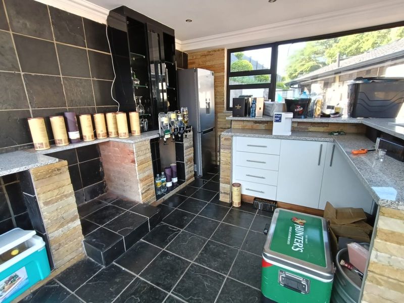 A dedicated bar area featuring stone wall accents, granite countertops, built-in cabinetry, and tiled flooring, providing a functional space for entertaining.