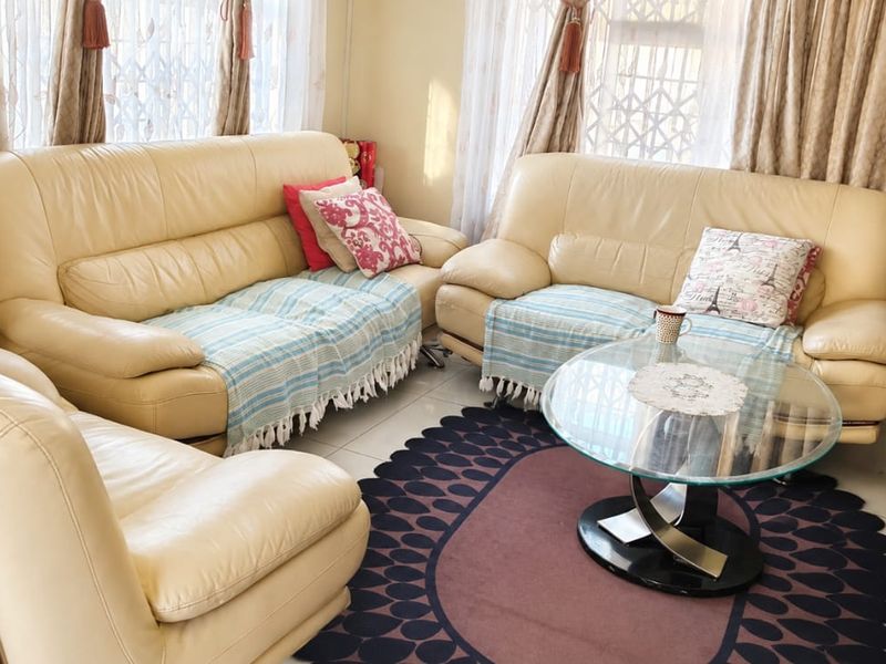 A comfortable living room featuring tiled flooring and natural light through large windows with security gates.