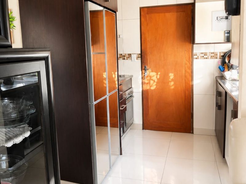 A functional kitchen featuring dark wood cabinetry, tiled flooring, a tiled backsplash, and a built-in oven with hob.