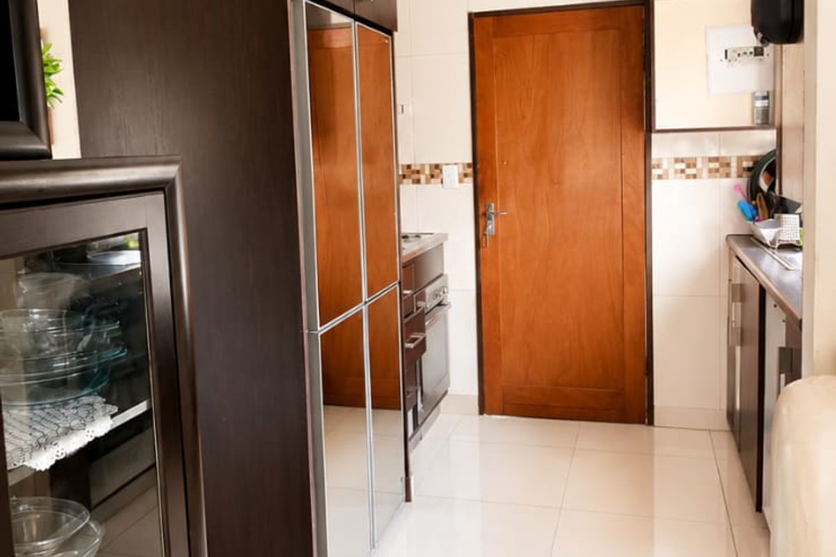 A functional kitchen featuring dark wood cabinetry, tiled flooring, and a tiled backsplash, providing a clean and practical workspace.